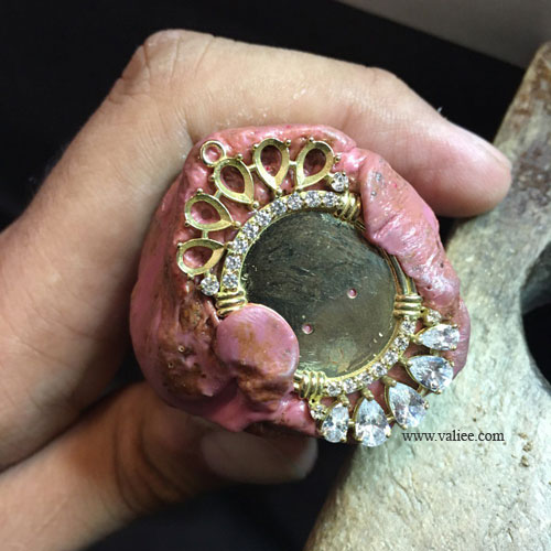 Hand stone setting of diamonds on an 18k gold Victorian-style keepsake pendant during final assembly, by Mehdi Valiee